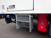 Seitenansicht eines LKWs mit Metallfach und roter Box.