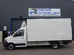 Weißer Lieferwagen vor einem Gebäude.