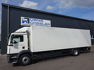 Weißer LKW neben einem Gebäude mit Beschilderung geparkt.