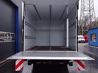 Ein offener LKW-Anhänger auf einem nassen Parkplatz.