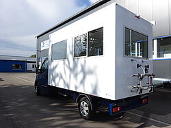 Weißer Transporter mit großem Aufbau und Fenstern