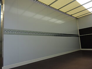 Leerer LKW-Innenraum mit Metallschienen.