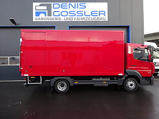 Roter LKW vor einer Werkstatt mit Firmenlogo