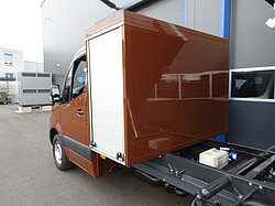 Brauner Lieferwagen vor einem Gebäude geparkt.