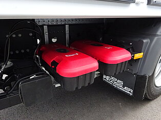 Rote Batteriedeckel unter einem LKW-Chassis.