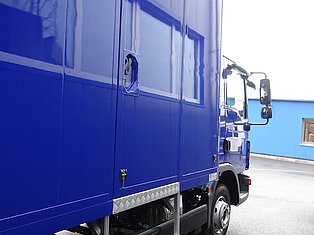 Seitenansicht eines blauen LKWs mit Trittleiter.
