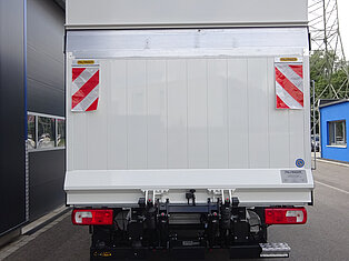 Rückansicht eines weißen LKWs mit roten Reflektoren.