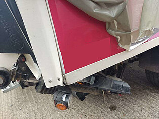 Nahaufnahme eines beschädigten Lkw-Hecks mit zerrissener Abdeckung.