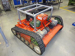 Ein roter gepanzerter Industrieroboter auf Werkstattboden.