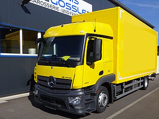 Gelber LKW vor einem Gebäude mit Denis Gossler Schild