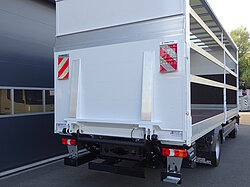 Rückansicht eines LKW mit offenem Aufbau vor Gebäude