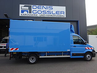 Blauer Lieferwagen vor einem Gebäude geparkt.