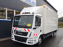 Weißer MAN-LKW vor einer Werkstatt geparkt.