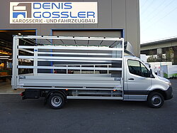 Silberner LKW vor einer Werkstatt mit Schild 'Denis Gossler'.