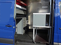 Offene Seitentür eines blauen Vans mit organisiertem Innenraum.