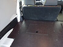 Innenraum eines Vans mit umgeklappten Rücksitzen und Holzboden.