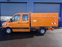 Oranges Nutzfahrzeug vor einer Garage geparkt.