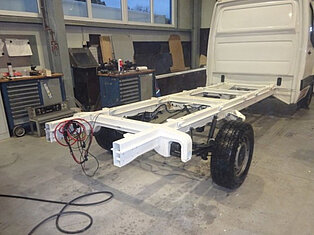 Ein Fahrzeugchassis in einer Werkstatt mit Werkzeugen.