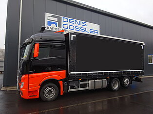 Schwarz-oranger LKW am Servicezentrum geparkt.