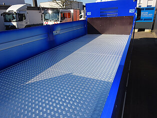 Leerer blauer LKW-Laderaum mit Metallboden.