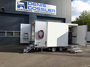 Ein mobiler Servicetrailer mit offenen Türen und Treppen.