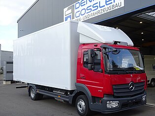 Roter und weißer LKW vor einem Gebäude geparkt.