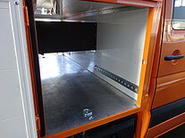 Offenes Staufach in einem orangefarbenen Van.