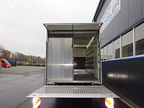 Ein offener LKW-Anhänger vor einem Gebäude.