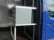 Innenraum eines Transporters mit Metallregalen und Schubladen.