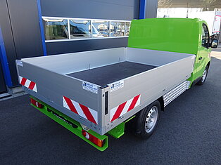 Grüner Pritschenwagen vor einem Gebäude geparkt.