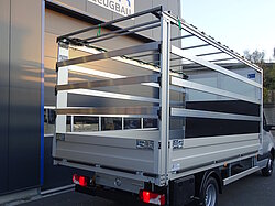 LKW mit offener Ladefläche vor Gebäude