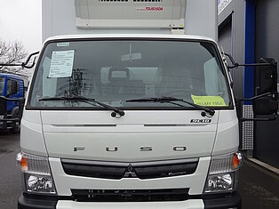Frontansicht eines weißen Kühltransporters vor einem Gebäude.
