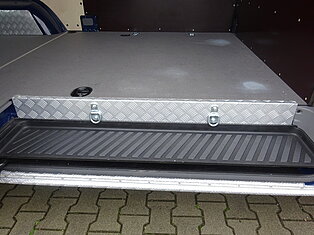 Offenes Fahrzeug-Staufach mit Metall- und Gummioberflächen.